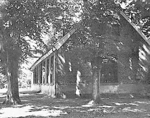 den gamle skolebygning på Buterland School omgivet af træer