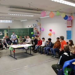 Õpilased ja õpetajad istuvad toolidest koosnevas ringis.