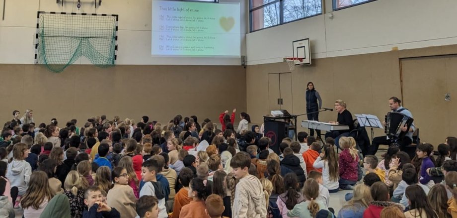 Les enfants sont assis dans le gymnase et chantent ensemble