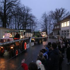 Des tracteurs traversent la cour de l'école et des enfants font des signes.