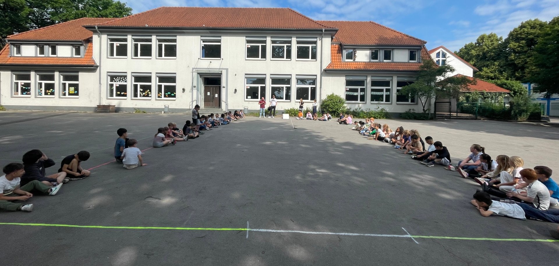 Anak-anak kelas dua menunggu dimulainya upacara di halaman sekolah