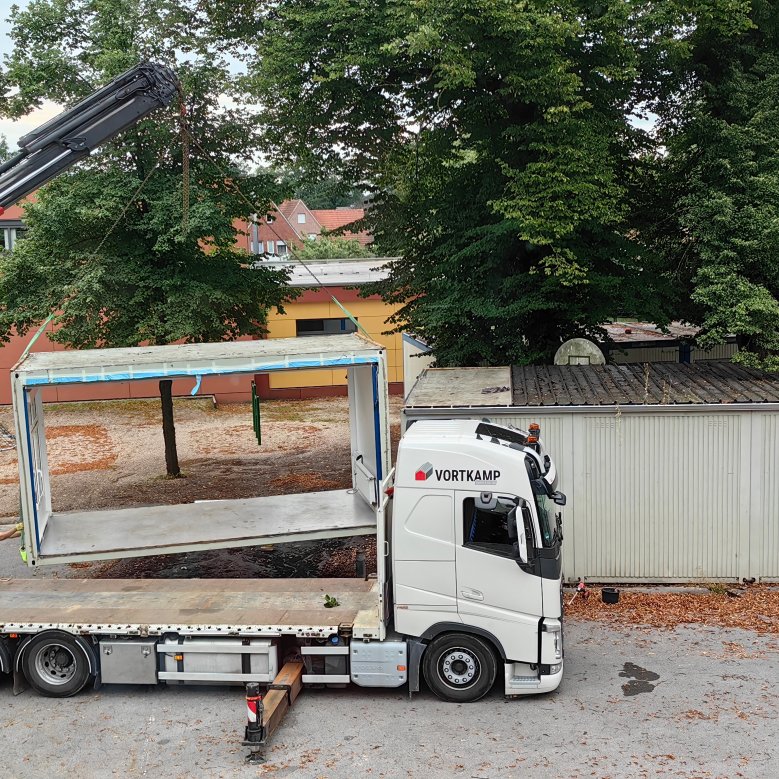 I vecchi contenitori vengono trasportati sul camion con una gru e rimossi.