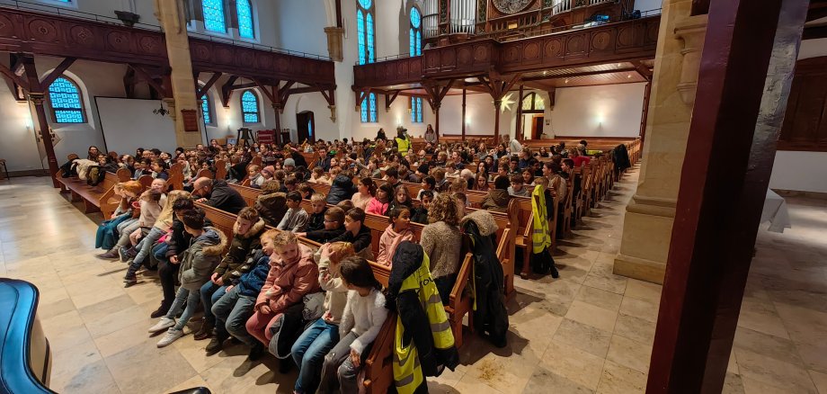 mokiniai sėdi bažnyčios suoluose.