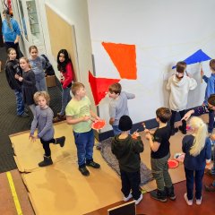 Bērni nokrāso sienu skolas ēkā