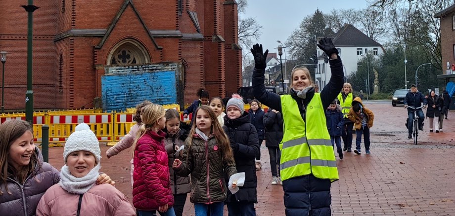 Kinderen en leerkracht lopen door de stad langs de protestantse kerk