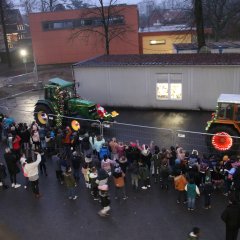 Ciągniki przejeżdżają przez plac szkolny, a dzieci machają