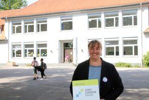 Frau Hüning mit der Plakette zum Startchancen-Programm, welches nun auch an der Buterlandschule anläuft.